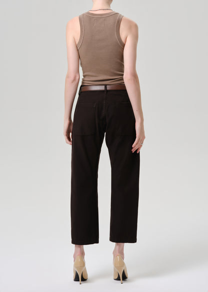 Person wearing a brown tank top and black pants on a grey background