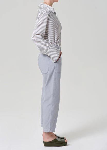 Person wearing a striped shirt and light gray pants on a grey background