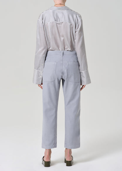 Person wearing a striped shirt and light gray pants on a grey background