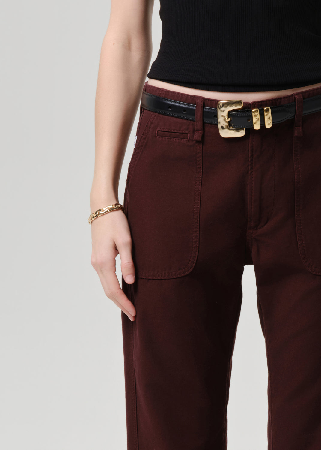 Brown pants with a gold belt buckle on a grey  background