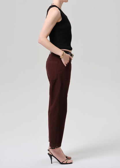 Person wearing a black sleeveless top and brown pants on a grey  background