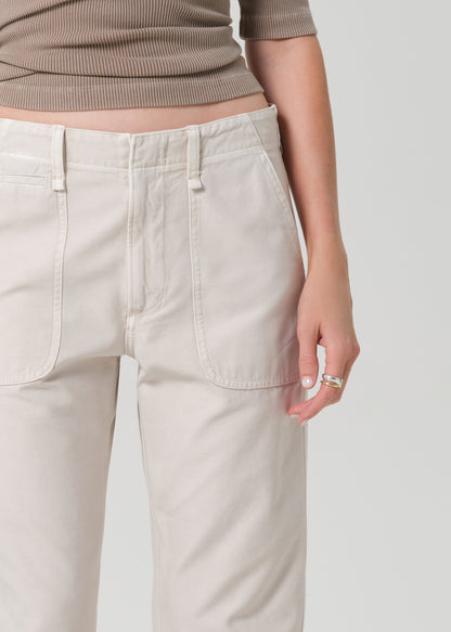 Person wearing a brown top and beige pants on a grey background