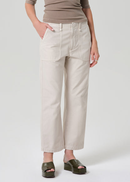 Person wearing a brown top and beige pants on a grey background