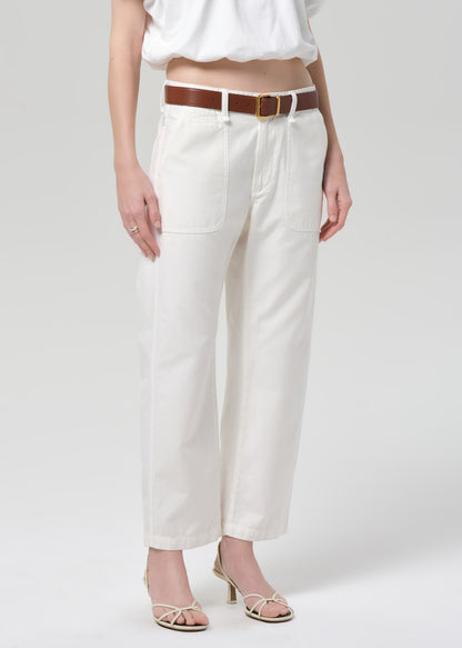 Person wearing white pants with a brown belt on a plain background