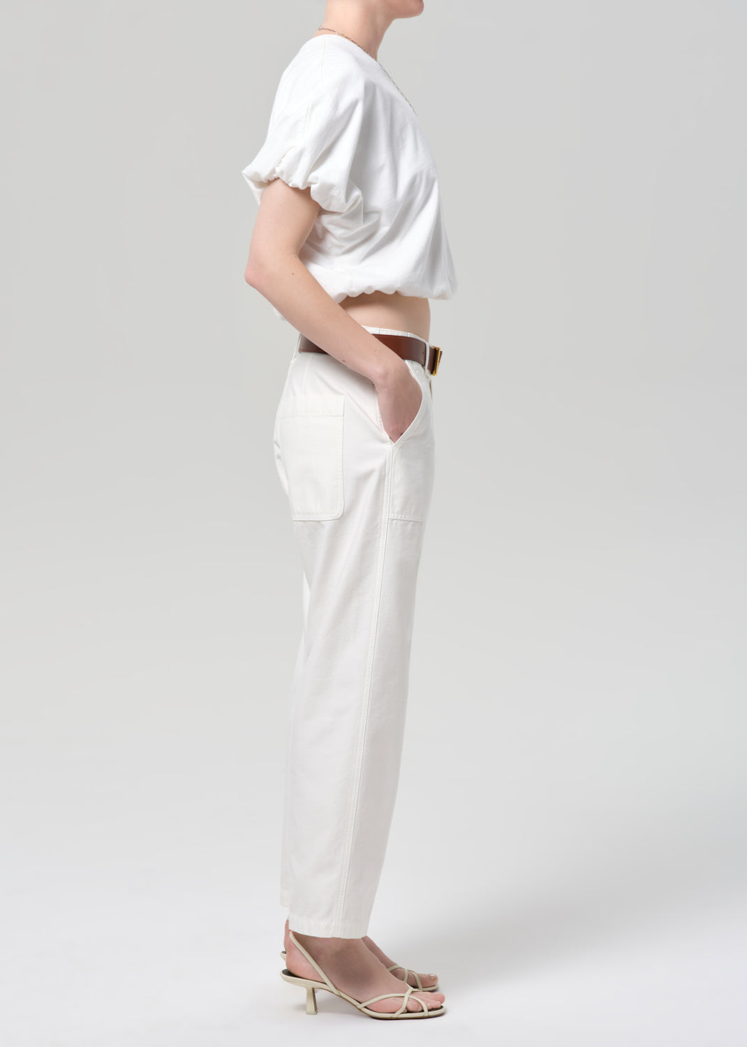 Person wearing a white outfit with a belt on a plain background