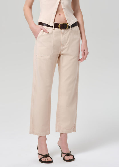 Person wearing a light peach outfit with a belt on a grey background