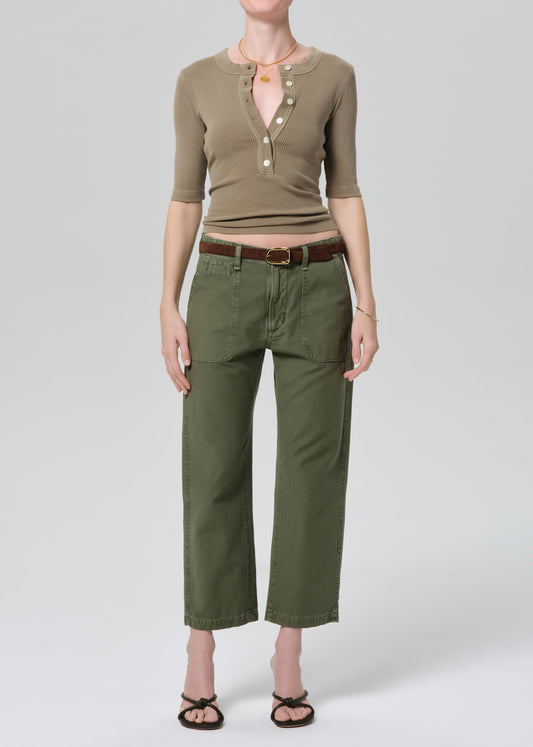 Person wearing a green top and olive green pants on a grey background
