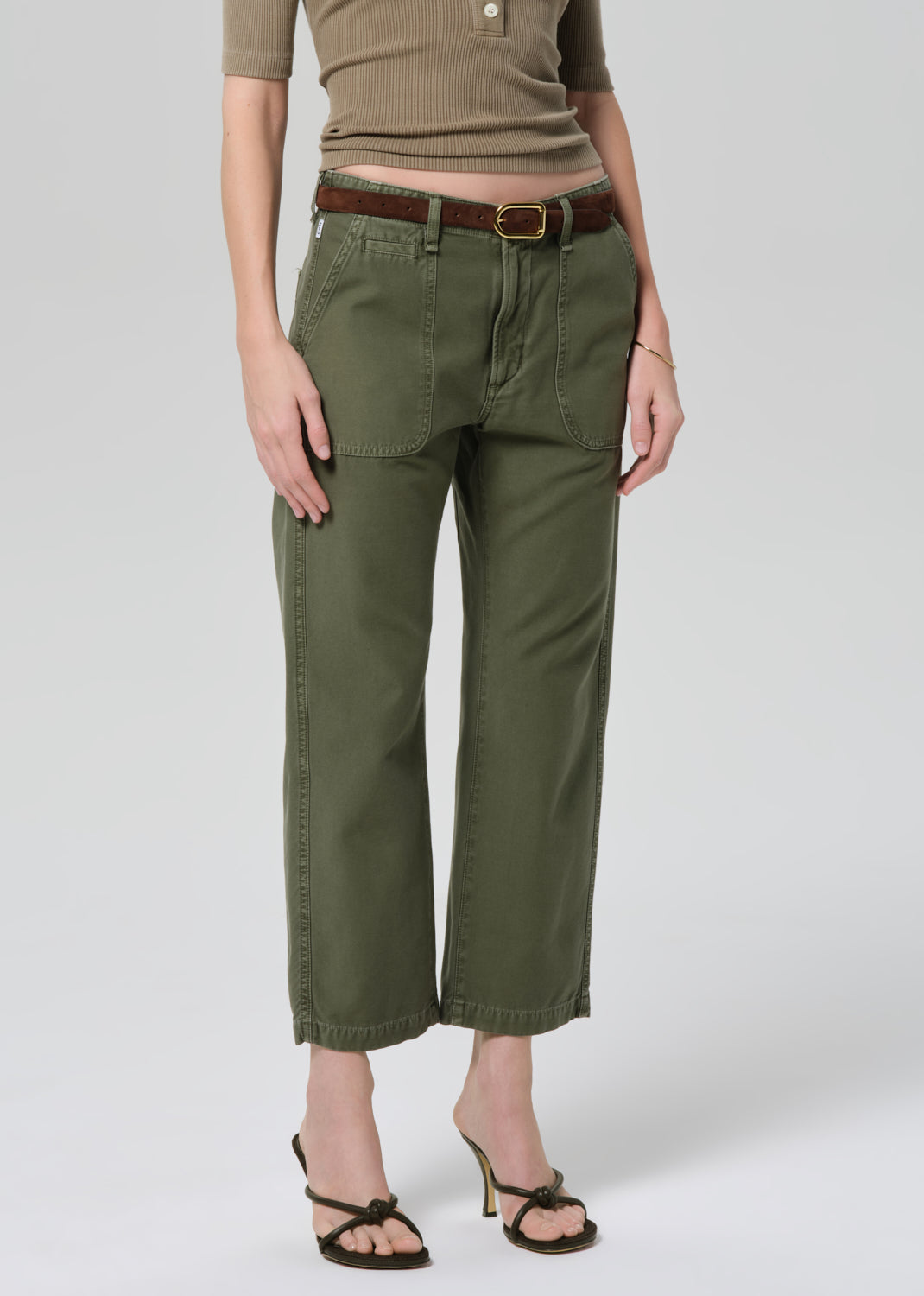 Person wearing a green top and olive green pants on a grey background