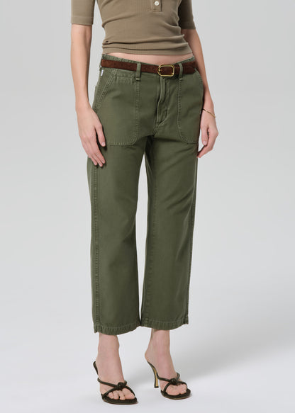 Person wearing a green top and olive green pants on a grey background