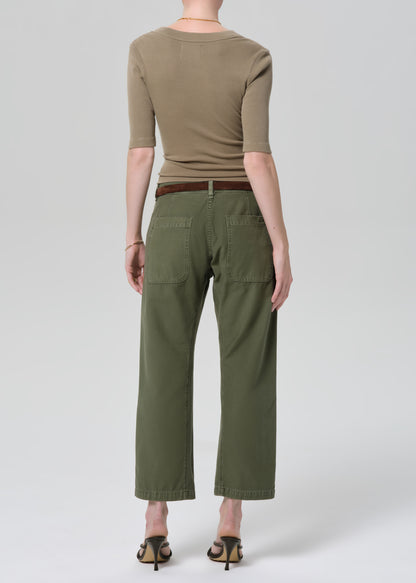 Person wearing a green top and olive green pants on a grey background