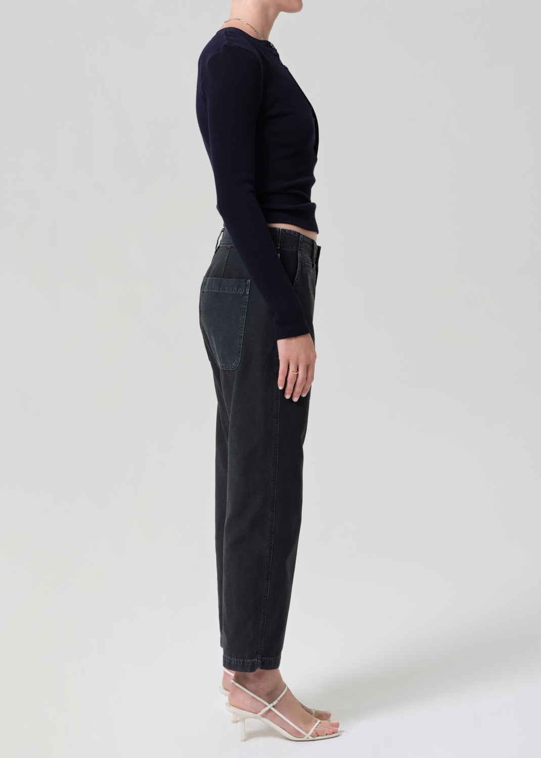 Person wearing a black long-sleeve top and black jeans on a grey background
