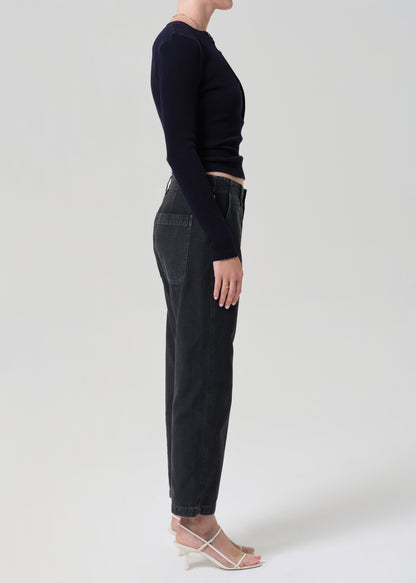 Person wearing a black long-sleeve top and black jeans on a grey background