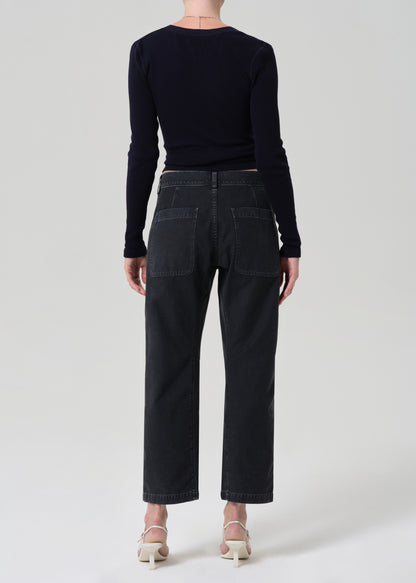 Person wearing a black long-sleeve top and black jeans on a grey background