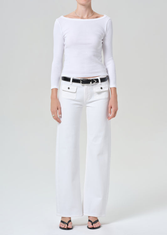 Person wearing a white long-sleeve top and white jeans on a plain background