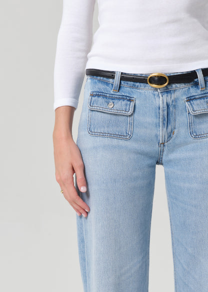 Light blue jeans with a black belt and gold buckle on a plain background