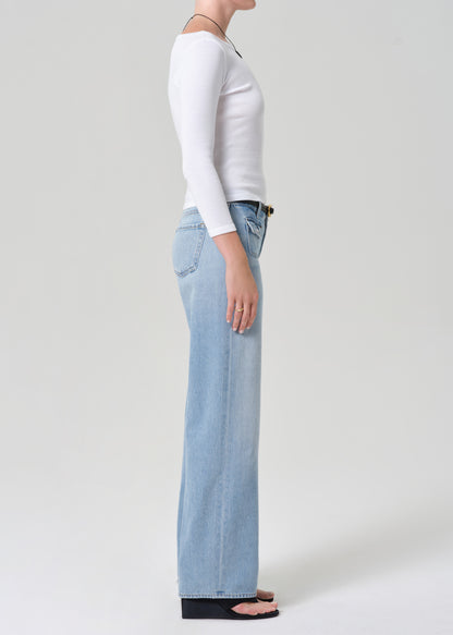 Person wearing light blue jeans and a white long-sleeve shirt on a plain background