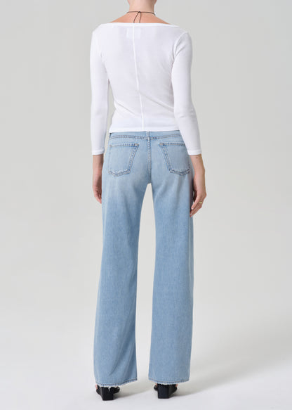 Person wearing light blue jeans and a white top on a plain background