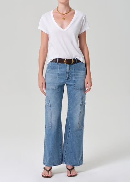 Person wearing a white t-shirt and blue jeans with a belt on a plain background