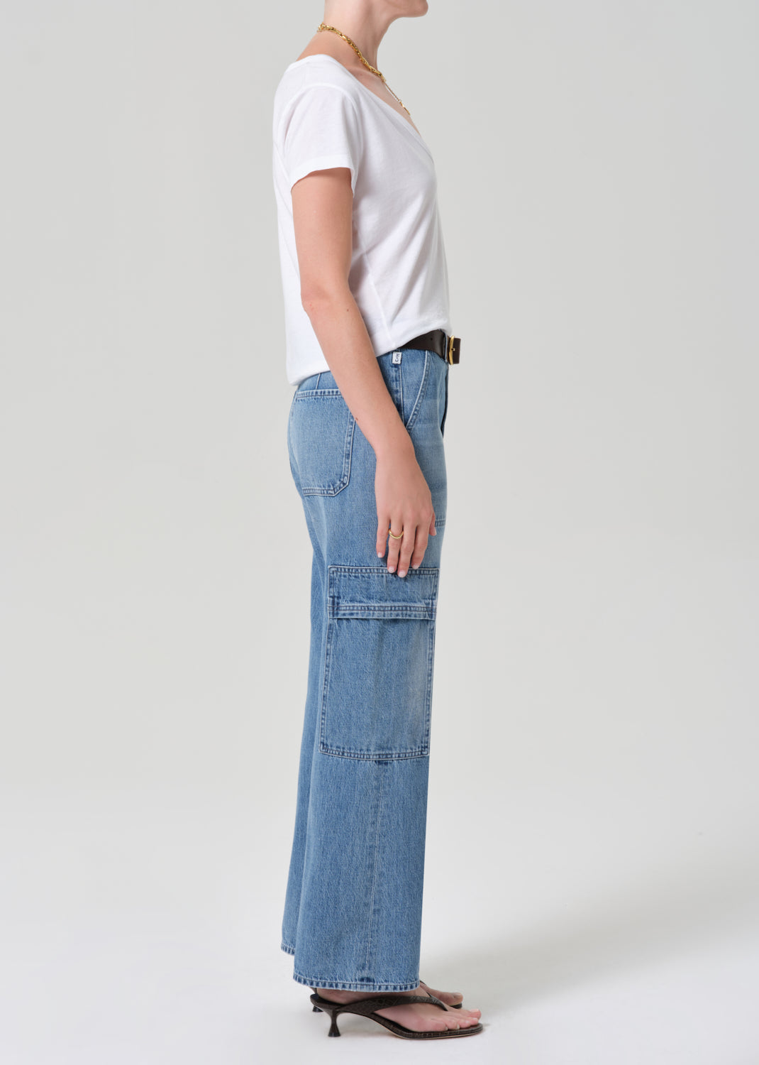 Person wearing a white t-shirt and blue jeans with a belt on a plain background