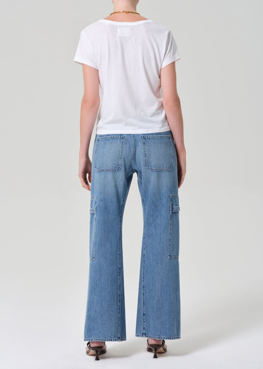 Person wearing a white t-shirt and blue jeans with a belt on a plain background