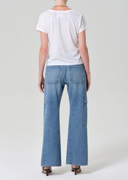 Person wearing a white t-shirt and blue jeans with a belt on a plain background