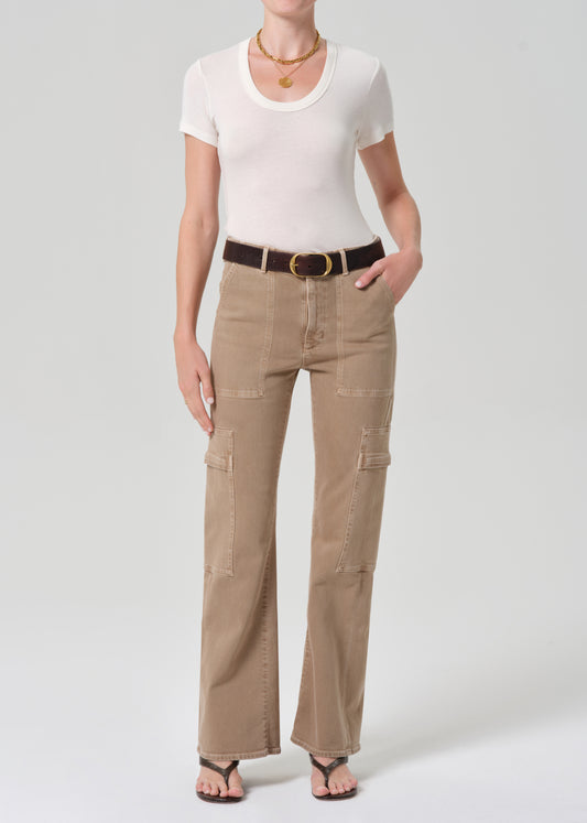 Woman wearing beige cargo pants and a white top on a plain background