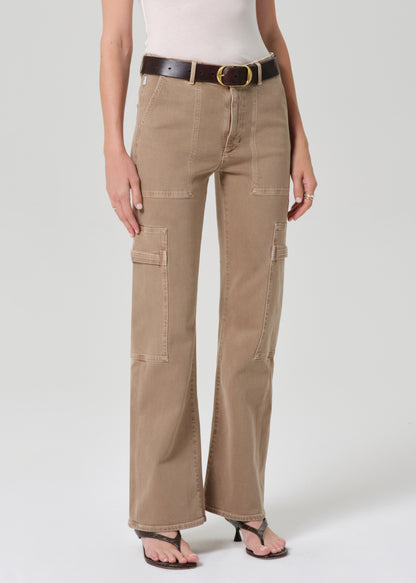 Woman wearing beige cargo pants and a white top on a plain background