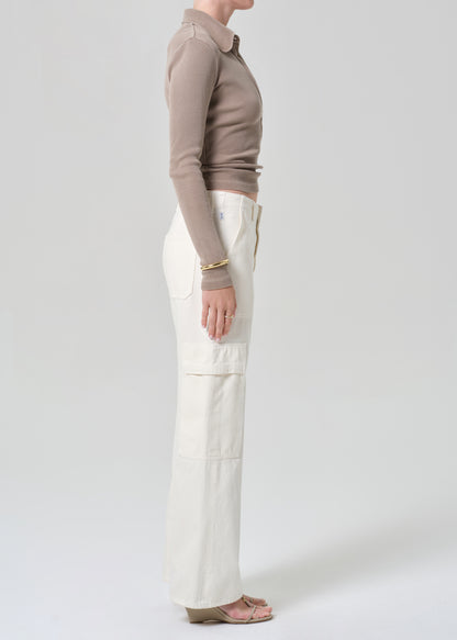 Person wearing a brown long-sleeve shirt and white pants on a light gray background