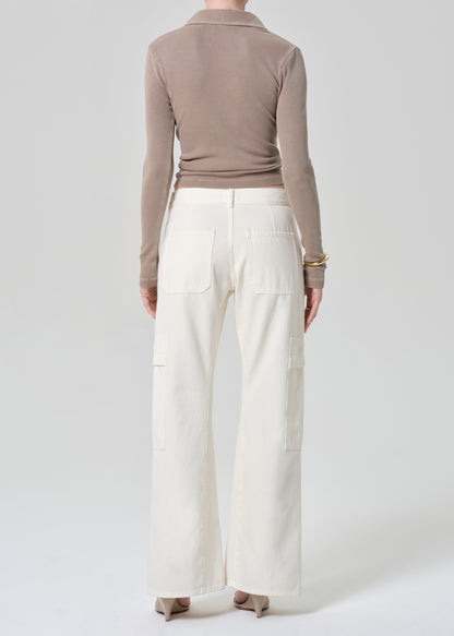 Person wearing a brown long-sleeve shirt and white pants on a light gray background