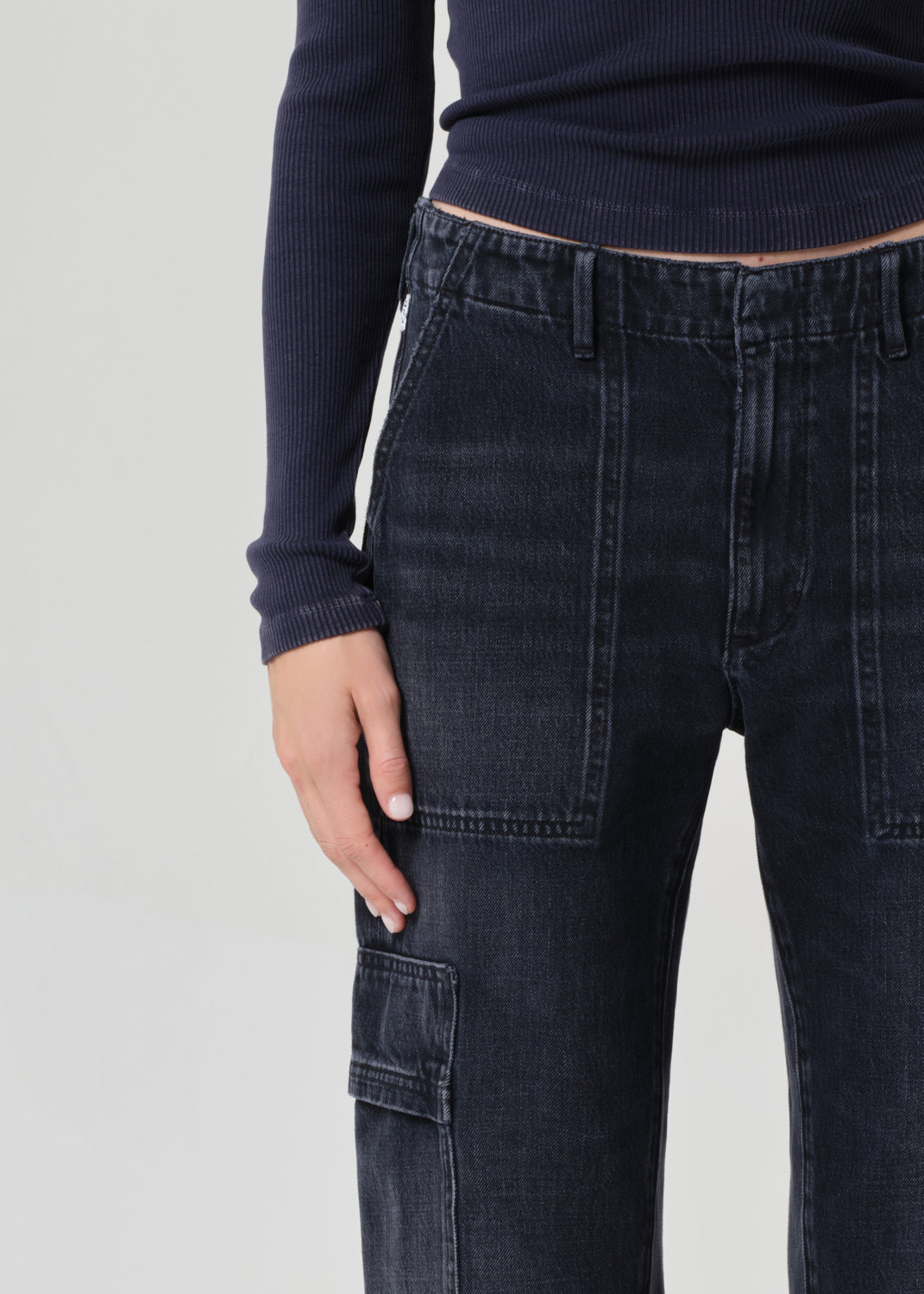 Person wearing a navy long-sleeve top and dark wash wide-leg jeans on a grey background