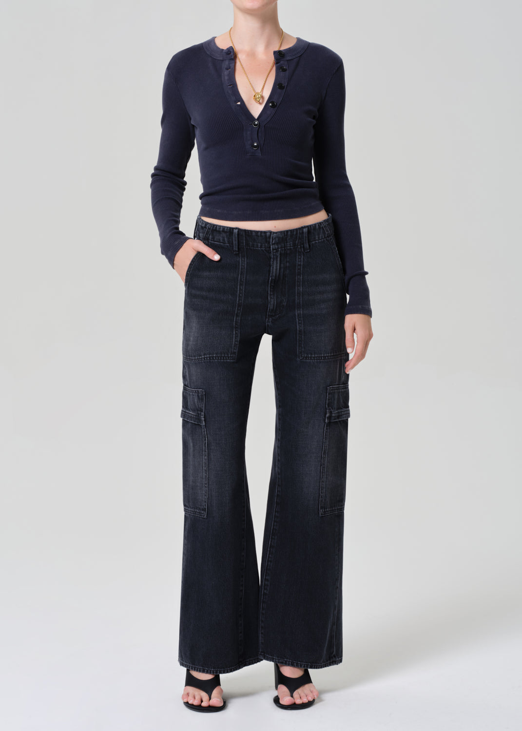 Person wearing a navy long-sleeve top and dark wash wide-leg jeans on a grey background