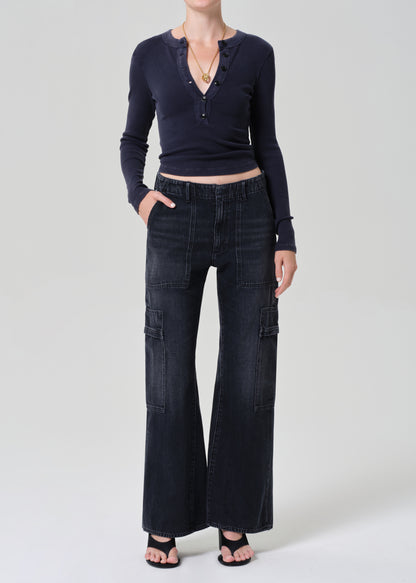 Person wearing a navy long-sleeve top and dark wash wide-leg jeans on a grey background