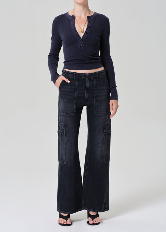 Person wearing a navy long-sleeve top and dark wash wide-leg jeans on a grey background