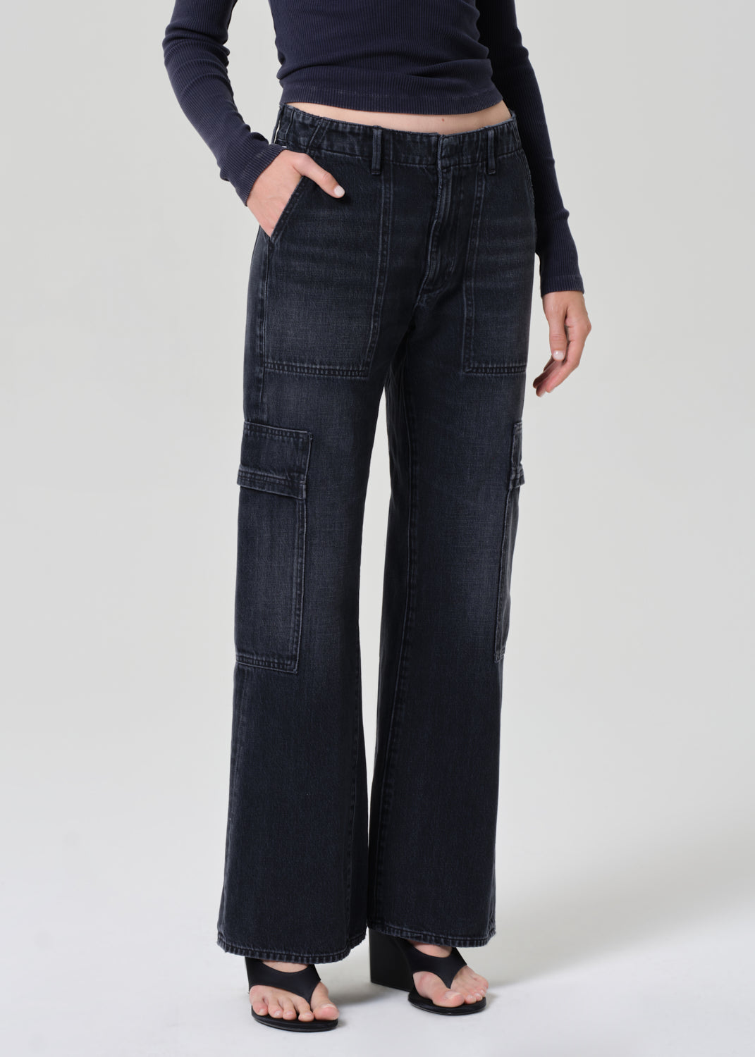 Person wearing a navy long-sleeve top and dark wash wide-leg jeans on a grey background