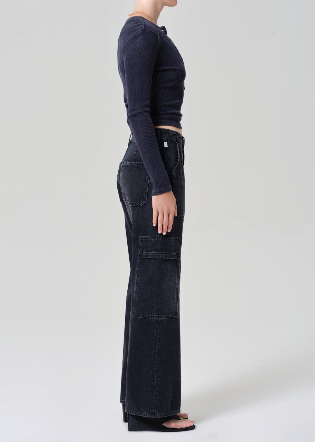 Person wearing a navy long-sleeve top and dark wash wide-leg jeans on a grey background