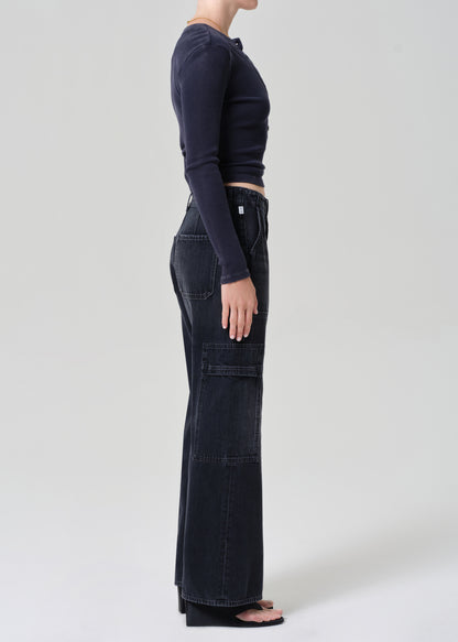 Person wearing a navy long-sleeve top and dark wash wide-leg jeans on a grey background