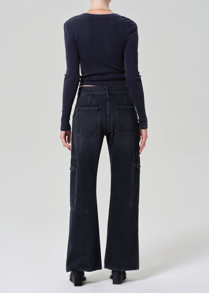 Person wearing a navy long-sleeve top and dark wash wide-leg jeans on a grey background