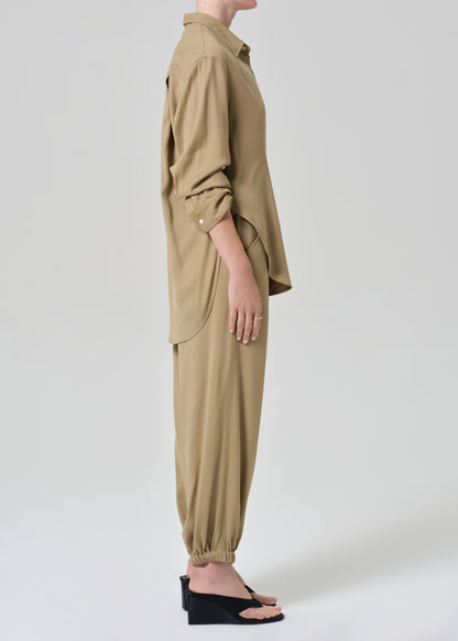 Person wearing a beige shirt and pants set on a grey background