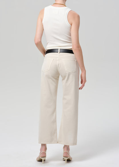 Person wearing a white sleeveless top and beige wide-leg pants on a light gray background