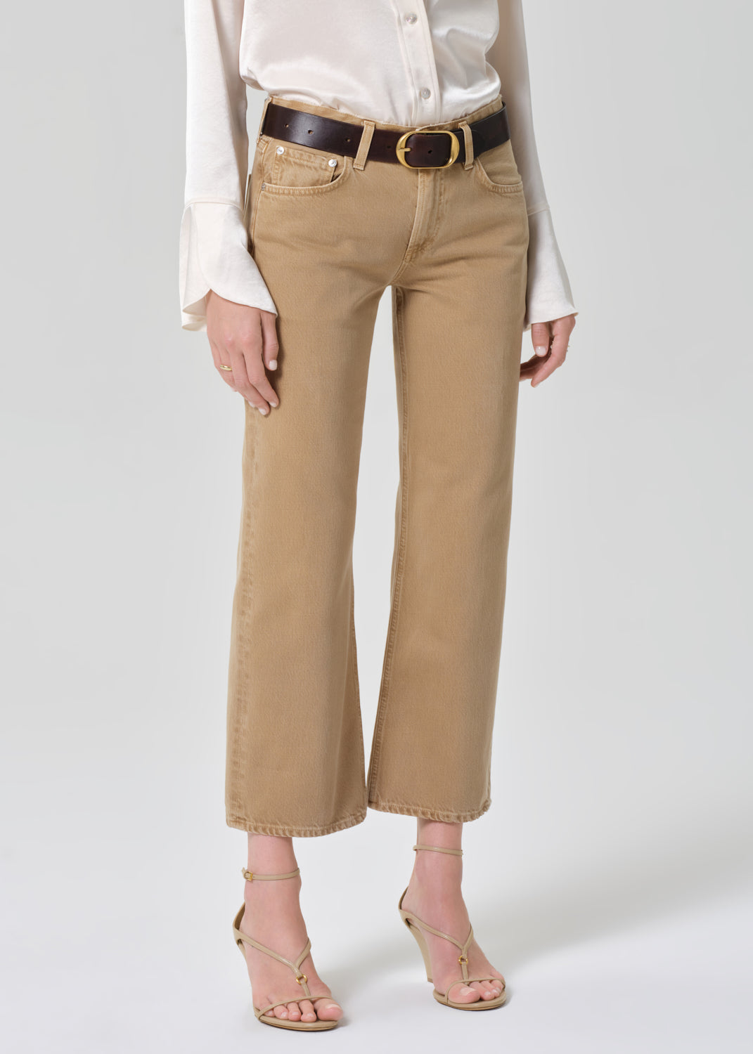 Person wearing beige pants with a white shirt on a plain background