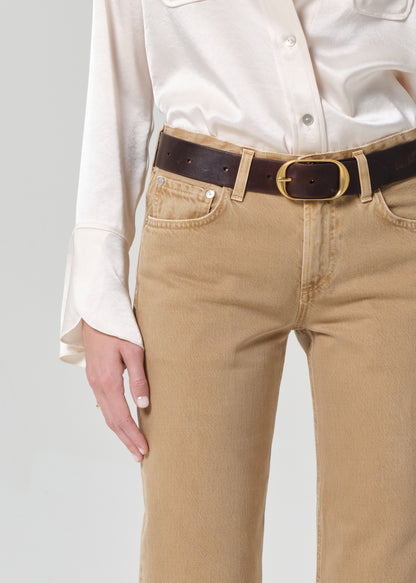 Person wearing beige pants with a brown belt on a plain background