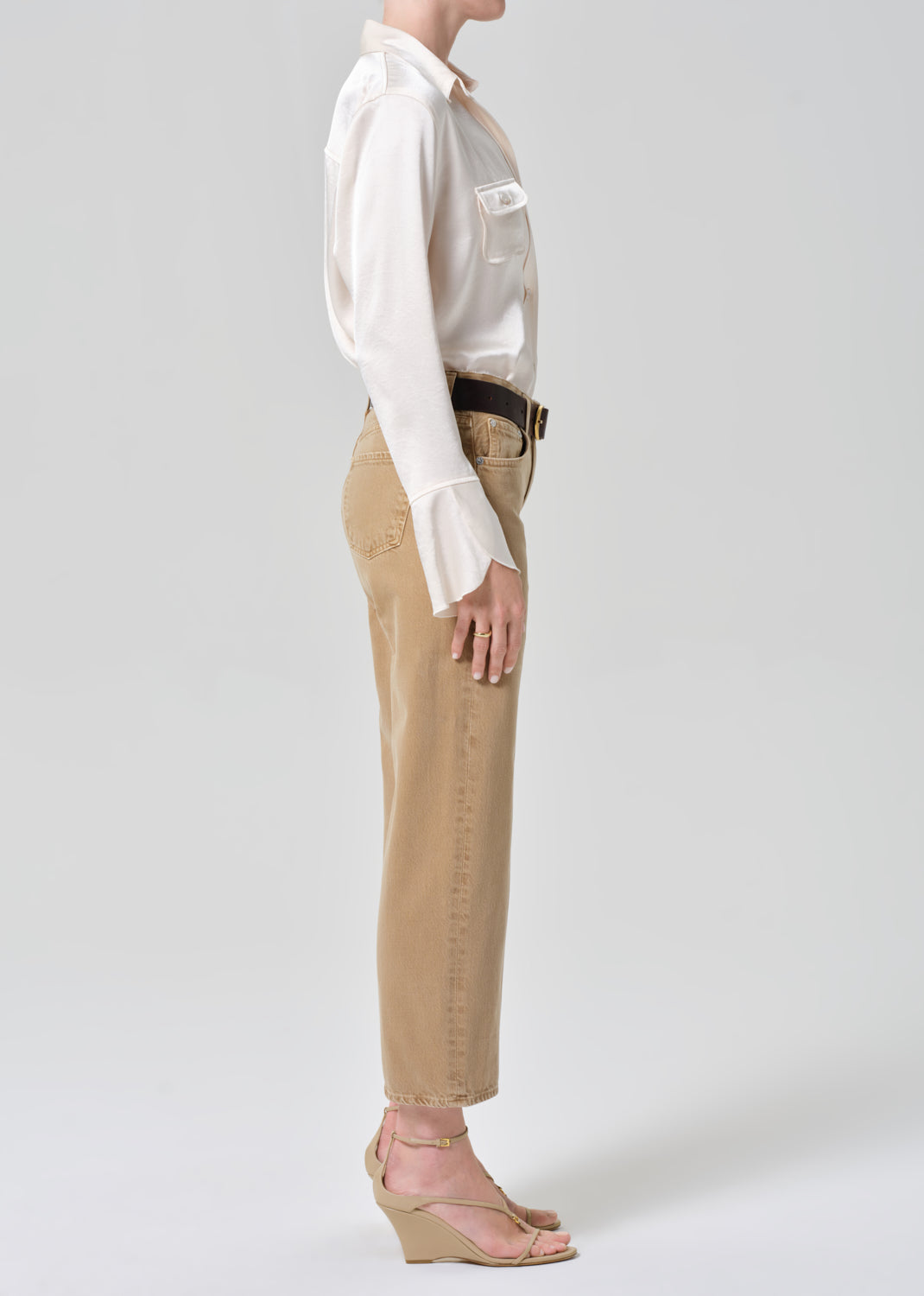 Person wearing a white shirt and beige pants on a plain background