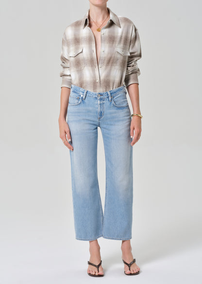 Person wearing a plaid shirt and light blue jeans on a plain background