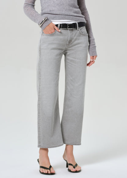 Person wearing gray wide-leg jeans and a gray sweater on a white background