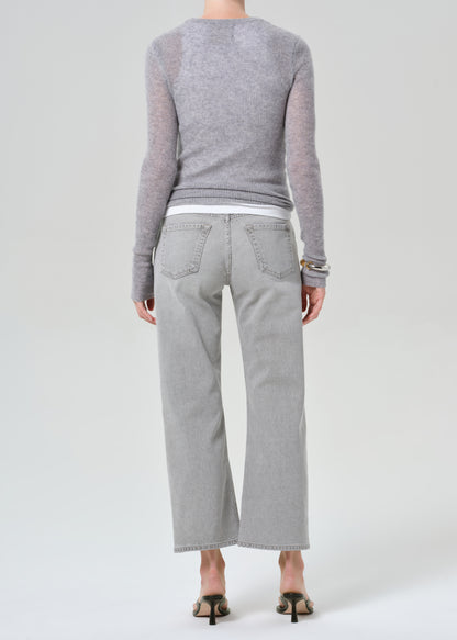 Person wearing a gray sweater and light gray pants on a white background