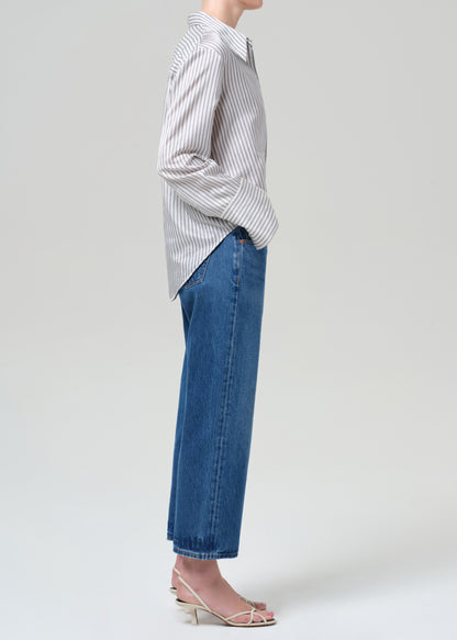 Person wearing a striped shirt and blue jeans on a plain background