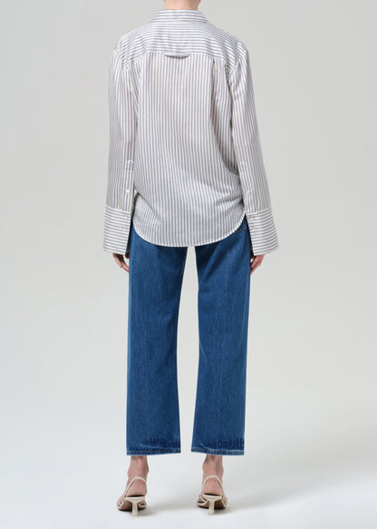Person wearing a striped shirt and blue jeans on a white background