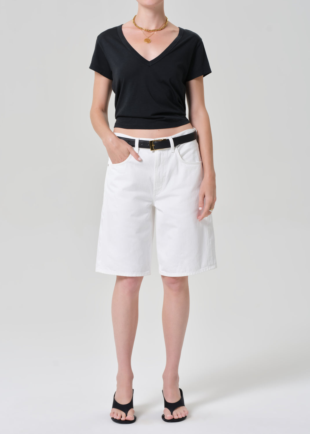 Person wearing a black tee and white denim shorts on a plain background