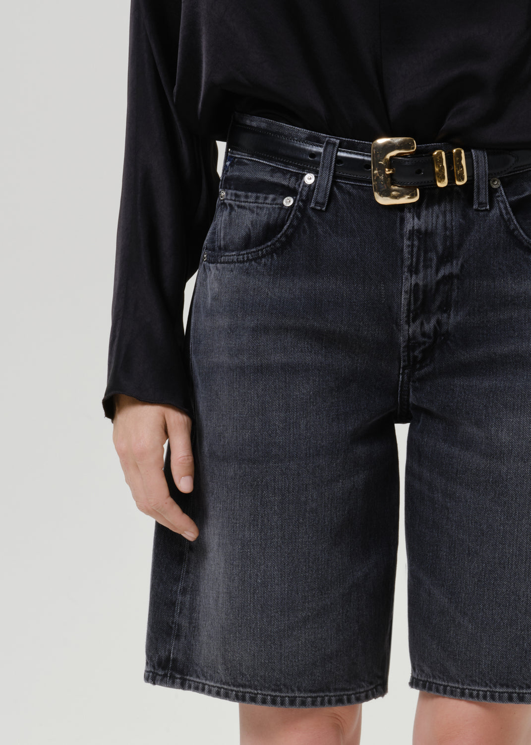 Close-up of black denim shorts on a grey background.