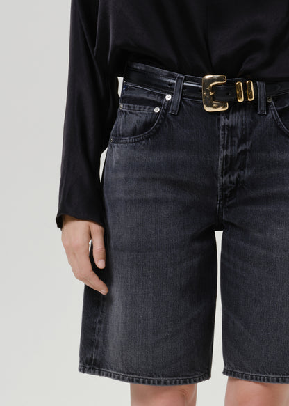 Close-up of black denim shorts on a grey background.
